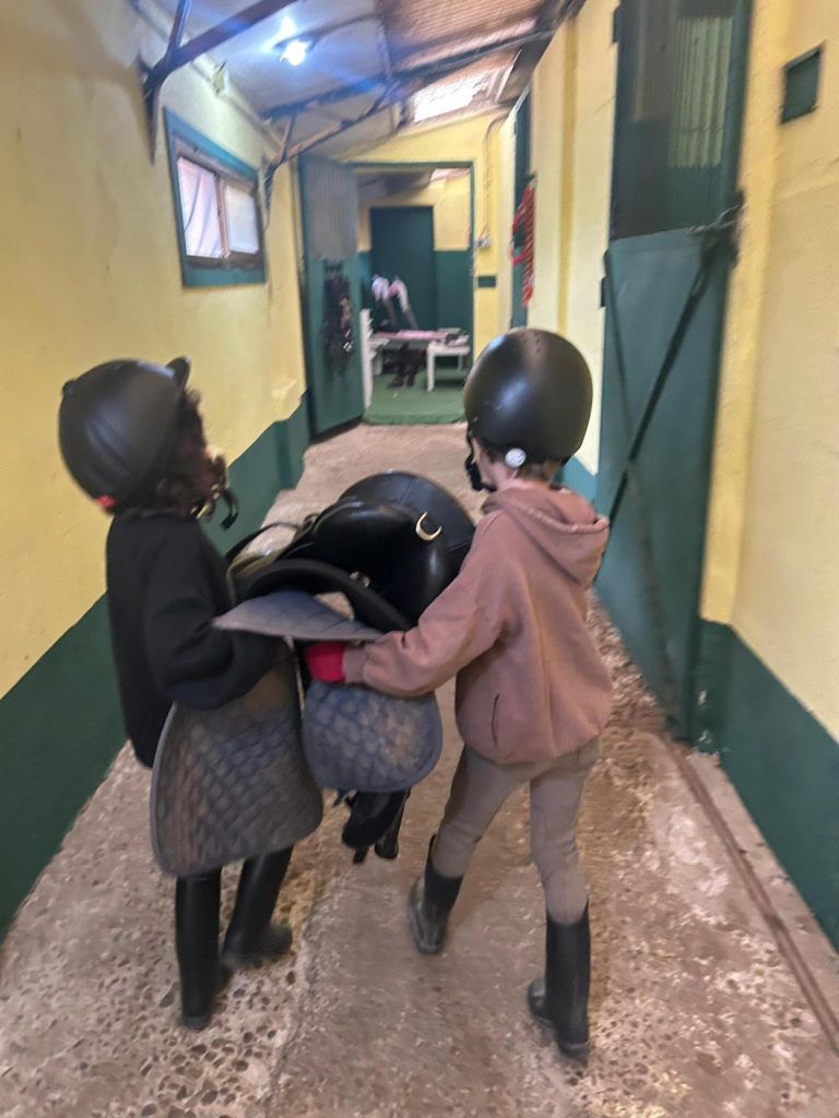 Niños llevando una silla de montar